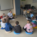 Bibliotekarka siedzi z dziećmi w kole na podłodze