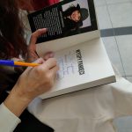 Zbliżenie na otwartą książkę z dedykacją, widoczna dłoń pisarki